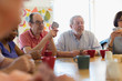 © Martin Barraud/Caia Image - Senior friends playing cards and drinking tea in community center