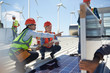 © Trevor Adeline/Caia Image - Female engineers talking, examining solar panels at power plant