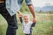 © Jarusha Brown/Caia Image - Father walking with baby son in grassy field