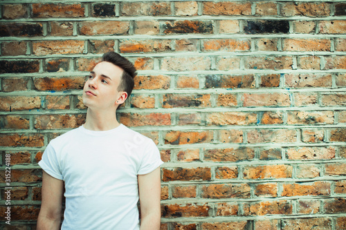 Thoughtful teenage boy standing at brick wall