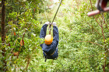 Woman Zip Lining Among Trees In Woods