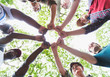 © Tom Merton/Caia Image - View from below mens group joining fists in circle, hiking under trees