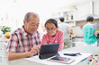 © Sam Edwards/Caia Image - Grandfather and granddaughter using digital tablet in kitchen