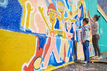 Mother And Son Volunteers Painting Vibrant Mural On Sunny Wall