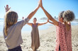 © Trevor Adeline/Caia Image - Women joining hands in circle on sunny beach during yoga retreat