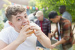 © Tom Merton/Caia Image - Portrait hungry teenage boy eating hamburger at backyard barbecue