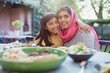 © Robert Daly/Caia Image - Portrait happy mother in hijab and daughter hugging at dinner table
