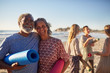 © Trevor Adeline/Caia Image - Portrait happy senior couple yoga mats on sunny beach during yoga retreat