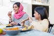 © Robert Daly/Caia Image - Happy mother in hijab and daughter eating dinner