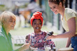 © Tom Merton/Caia Image - Young woman paying waitress with credit card at sunny sidewalk cafe