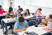 Junior High School Students Studying At Desks In Classroom