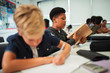 © Paul Bradbury/Caia Image - Junior high school boy opening notebook at desk in classroom