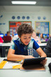 © Paul Bradbury/Caia Image - Junior high school boy student using digital tablet in classroom