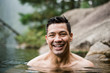 © Jarusha Brown/Caia Image - Portrait smiling, handsome young man swimming in lake
