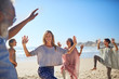 © Trevor Adeline/Caia Image - Group dancing on sunny beach during yoga retreat