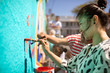 © Trevor Adeline/Caia Image - Smiling female volunteer painting mural on sunny wall