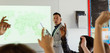 © Chris Ryan/Caia Image - Male high school teacher leading lesson at projection screen in classroom