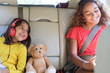 © Sam Edwards/Caia Image - Happy sisters and teddy bear riding in back seat of car