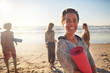 © Trevor Adeline/Caia Image - Portrait happy woman with yoga mat on sunny beach during yoga retreat