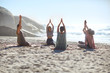 © Trevor Adeline/Caia Image - Serene people in circle meditating on sunny beach during yoga retreat