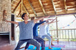 © Trevor Adeline/Caia Image - Happy woman practicing yoga warrior 2 pose in hut during yoga retreat