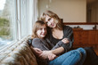 © Jarusha Brown/Caia Image - Portrait affectionate mother and daughter cuddling on living room sofa