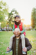 © Robert Daly/Caia Image - Portrait playful son riding on fathers shoulders in autumn park