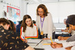 © Chris Ryan/Caia Image - Female high school teacher helping girl student studying at table in classroom