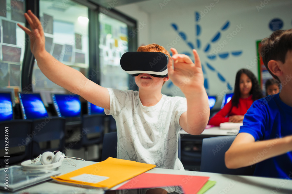 Curious junior high school boy student using virtual reality simulator ...