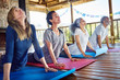 © Trevor Adeline/Caia Image - Serene group practicing upward facing dog pose in hut during yoga retreat