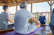 © Trevor Adeline/Caia Image - Female yoga instructor leading class in hut during yoga retreat