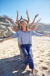 © Trevor Adeline/Caia Image - Portrait happy yoga class arms outstretched behind woman on sunny beach during yoga retreat