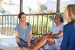 © Trevor Adeline/Caia Image - Smiling man and woman talking in hut during yoga retreat