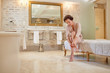 © Trevor Adeline/Caia Image - Woman putting on high heel sandals in luxury hotel bathroom