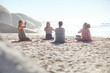 © Trevor Adeline/Caia Image - Group meditating in circle on sunny beach during yoga retreat