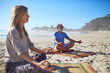 © Trevor Adeline/Caia Image - Serene people meditating on sunny beach during yoga retreat