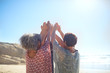© Trevor Adeline/Caia Image - Women with arms raised in circle on sunny beach during yoga retreat