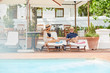 © Trevor Adeline/Caia Image - Mature couple relaxing on lounge chairs at resort poolside