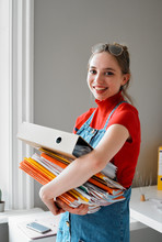 Portrait Confident Young Female College Student Carrying Stack Of Books Binder