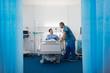 © Sam Edwards/Caia Image - Male nurse talking with patient resting in hospital room