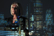 © Paul Bradbury/Caia Image - Double exposure thoughtful businesswoman against highrise lights at night