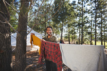 Portrait Happy Man Hanging Laundry On Campsite Clothesline In Woods