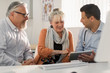 © Tom Merton/Caia Image - Doctor with digital tablet meeting with couple in doctors office