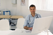 © Tom Merton/Caia Image - Portrait confident male doctor working at computer in doctors office