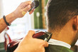 © Trevor Adeline/Caia Image - Close up male barber using trimmer on hair of customer