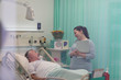 © Tom Merton/Caia Image - Doctor with medical chart talking with senior patient in hospital room