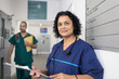 © Sam Edwards/Caia Image - Portrait confident female doctor with medical chart, making rounds in hospital corridor