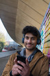 © Tom Merton/Caia Image - Portrait smiling young man listening to music with headphones and mp3 player