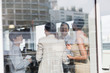© Tom Merton/Caia Image - Smiling business people talking at sunny office window