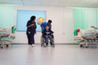 © Tom Merton/Caia Image - Doctor and nurse pushing boy patient in wheelchair in hospital ward